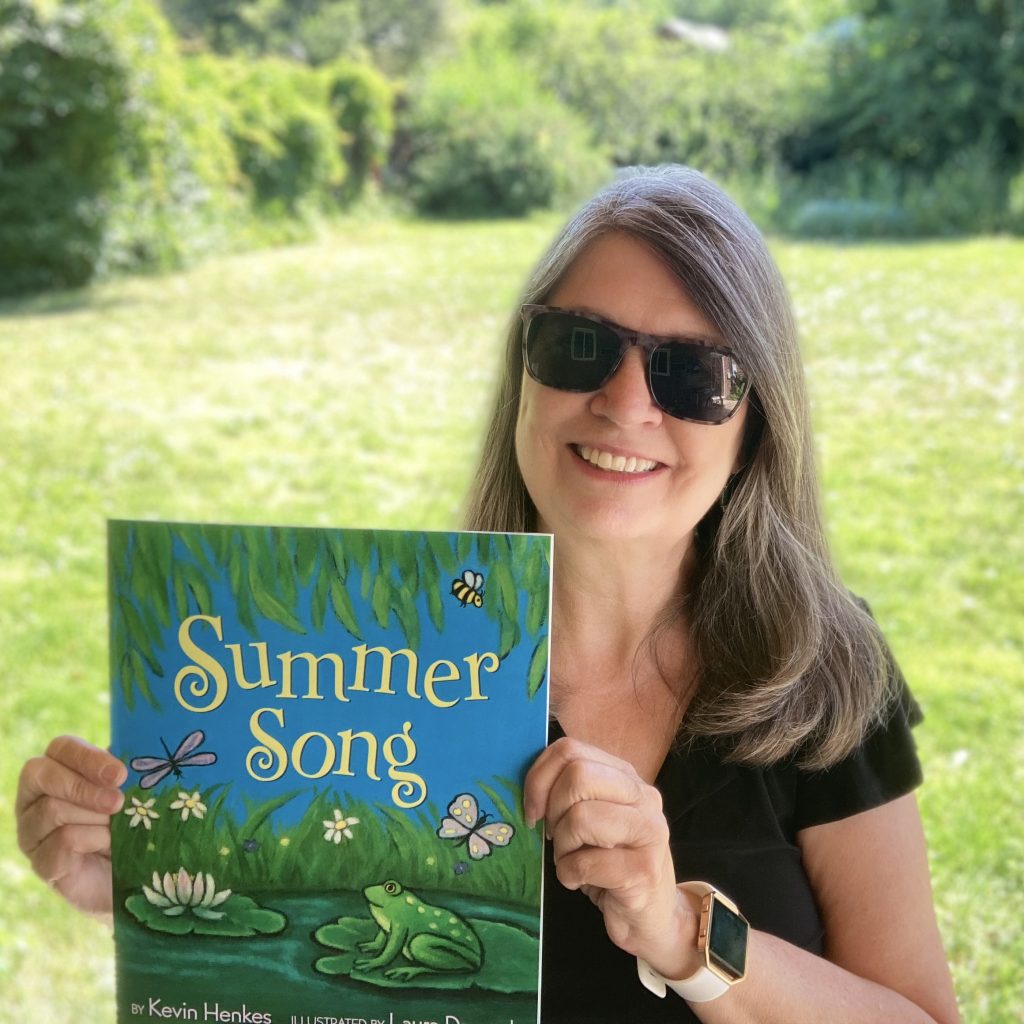 Picture of woman holding the book Summer Song.