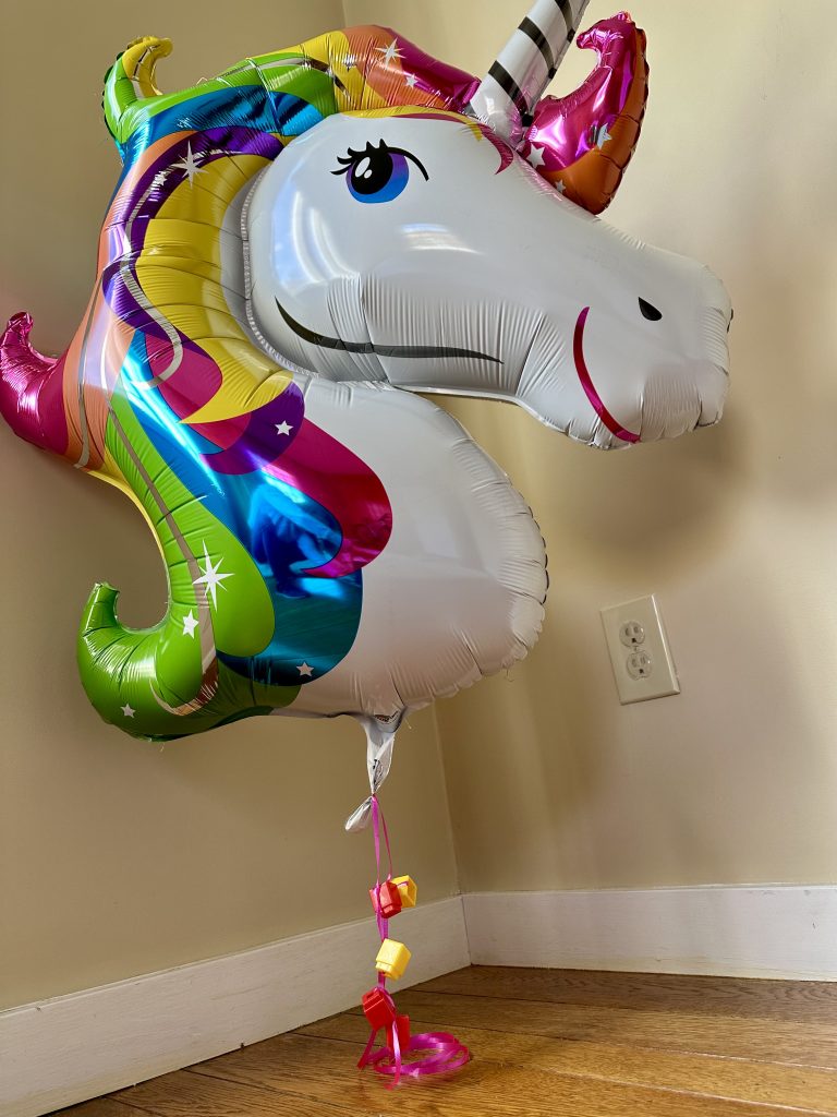 unicorn balloon with unifix cubes attached to the string to hold it down.